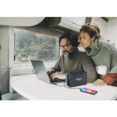 Ein Mann und eine Frau sitzen in einem Wohnmobil. Der Mann nutzt einen Laptop, der an eine tragbare Stromstation angeschlossen ist.