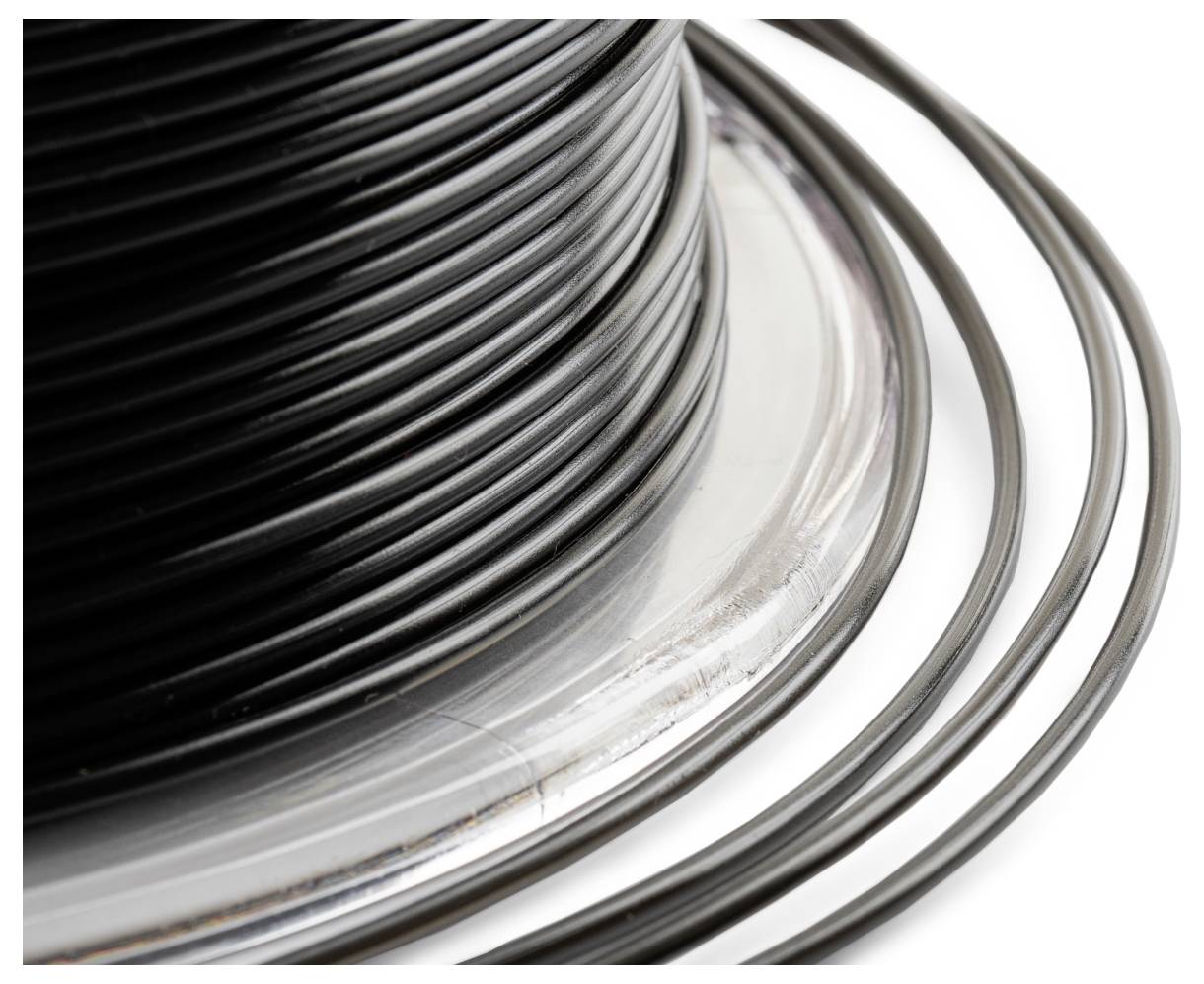 Eine große Rolle mit schwarzem Draht auf einer silbernen Spule. Der Draht ist eng gewickelt und einige Schlaufen liegen locker auf der Oberfläche.