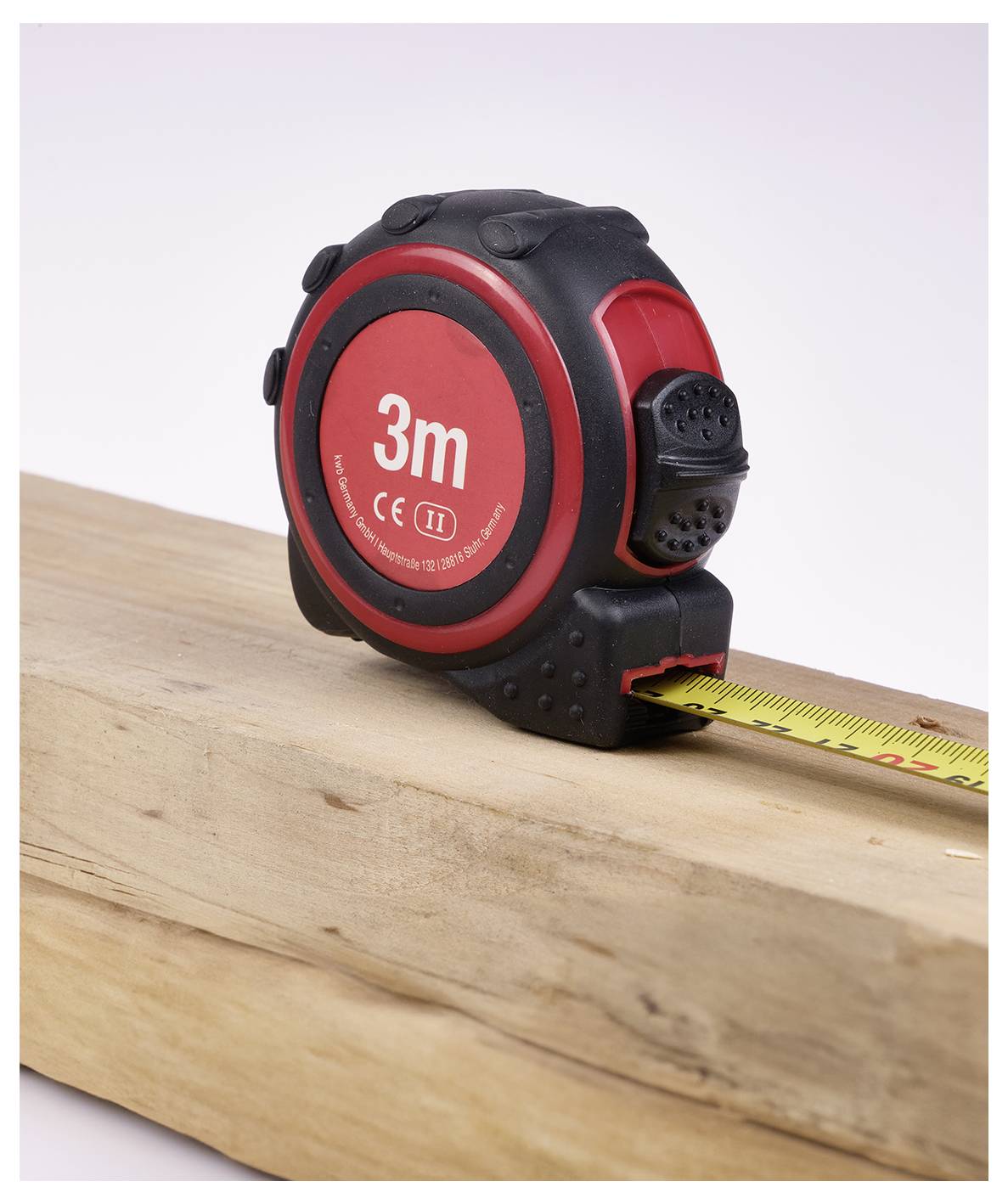 Ein rot-schwarzes Maßband mit der Beschriftung '3m' ist auf einem Holzbrett ausgelegt und zeigt seine Verwendung zum Längenmessen.