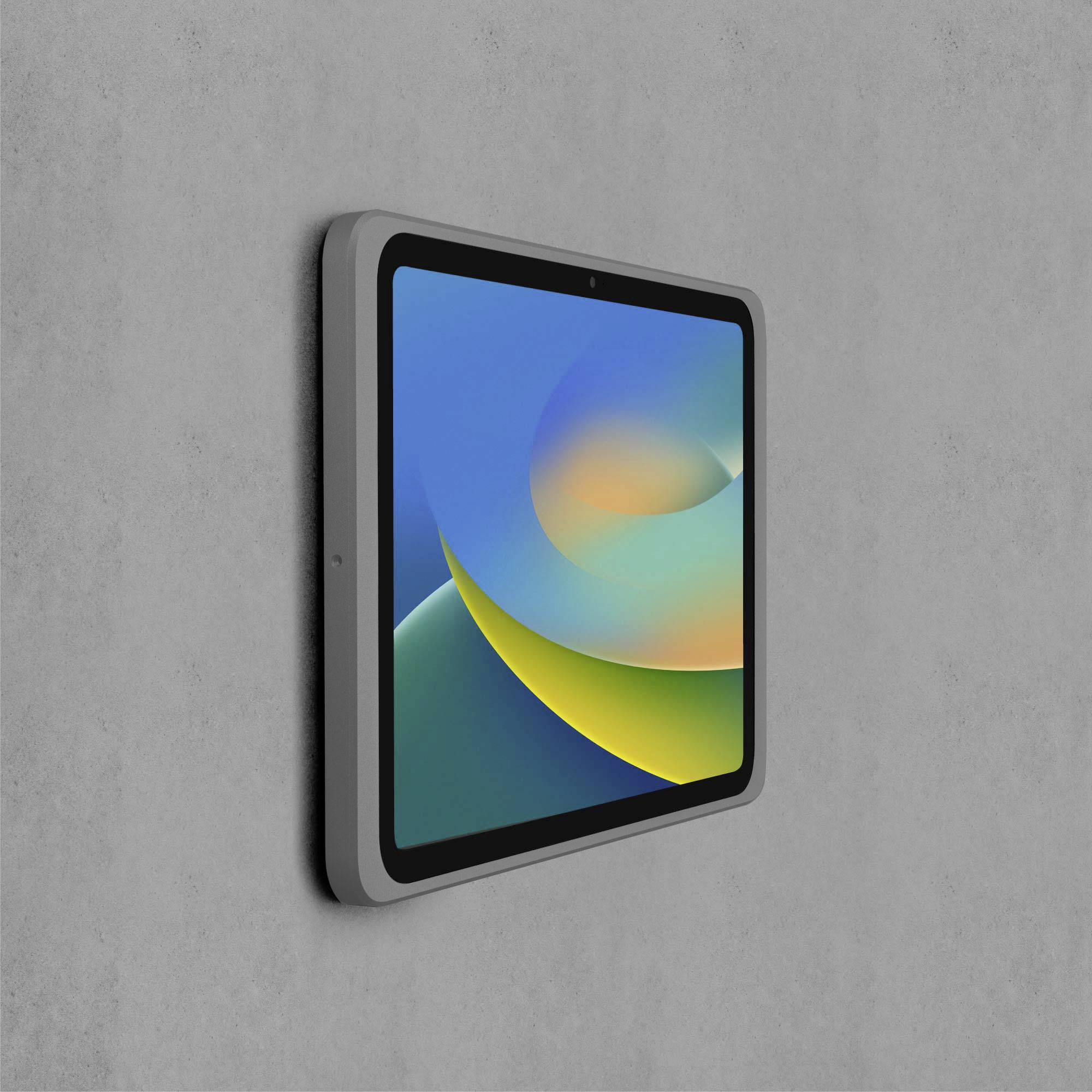 Ein Tablet mit buntem, abstraktem Bildschirm, montiert an einer grauen Wand.