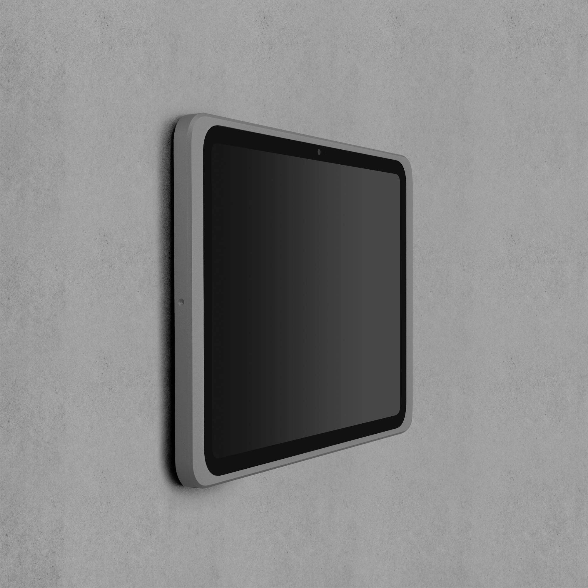 Ein graues Tablet ist an einer Wand montiert. Der Bildschirm ist ausgeschaltet.