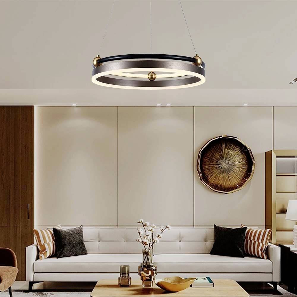 Moderne Wohnzimmergestaltung mit einem weißen Sofa, dekorativen Kissen, einem runden Kronleuchter und einem Zierobjekt an der Wand.