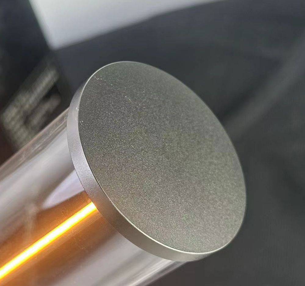 Zylinderförmiger Gegenstand mit einer leuchtenden orangen Linie in der Mitte, vermutlich Teil eines technischen Geräts oder einer Lampe.
