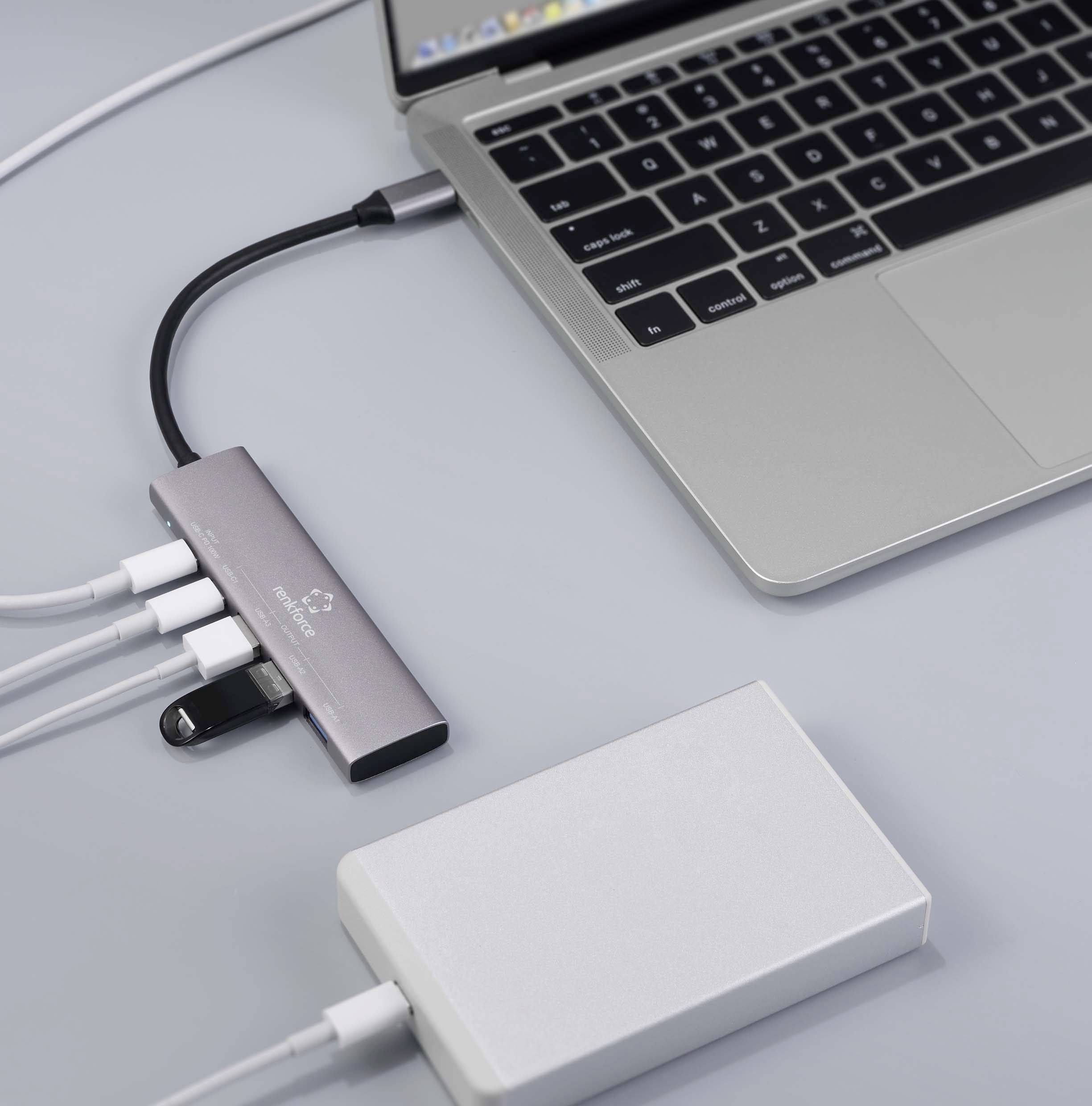 Ein Laptop mit angeschlossenem USB-Hub, an den mehrere Geräte gekoppelt sind, darunter ein USB-Stick und ein externer Akku.
