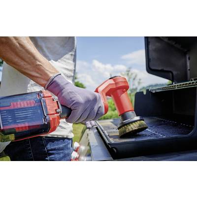 Eine Person reinigt den Grillrost eines Grills im Freien mit einer roten elektrischen Reinigungsbürste.
