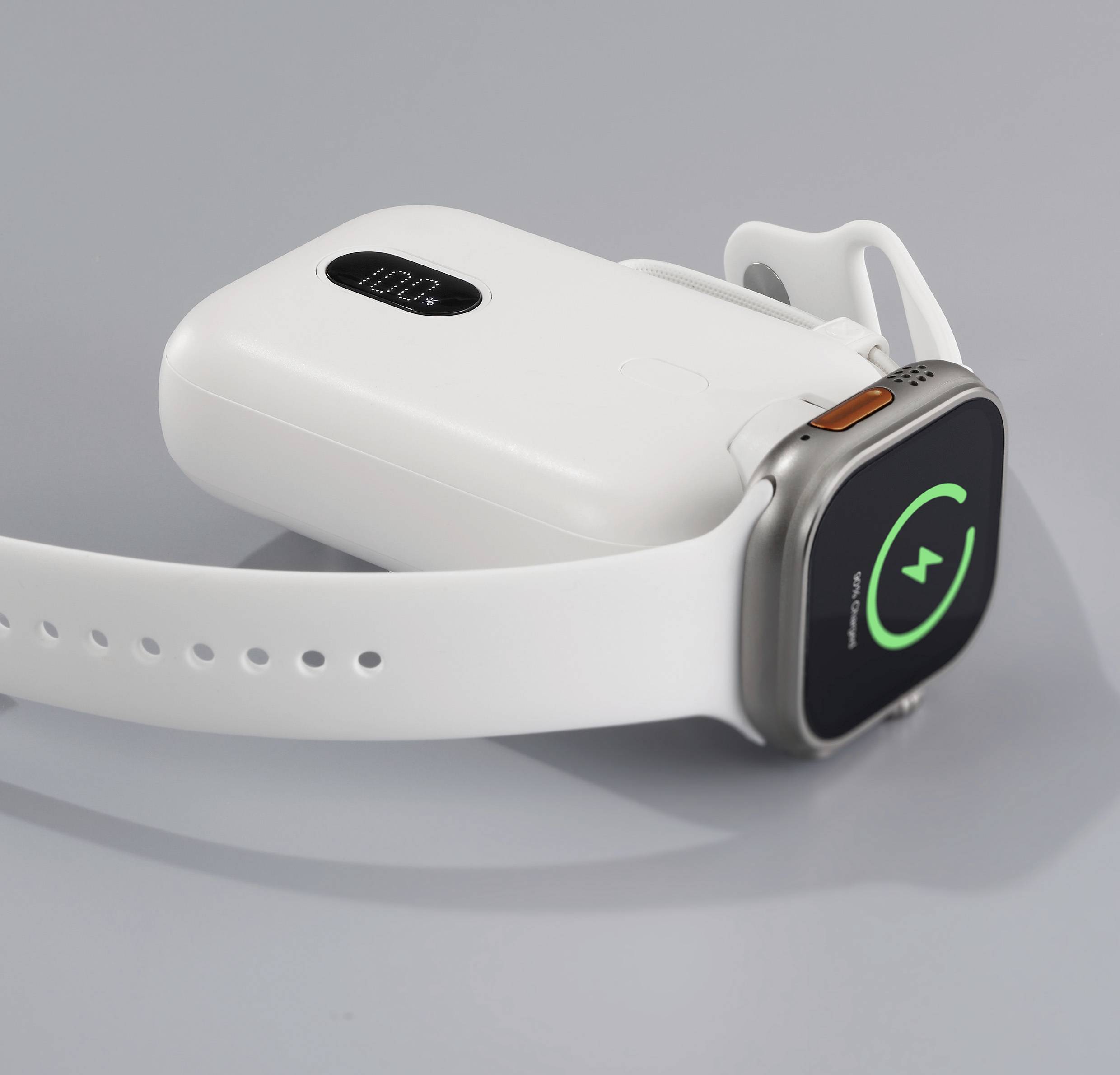 Eine Smartwatch mit weißen Armband lädt kabellos auf einem Ladegerät. Auf dem Display ist ein grüner Ladering zu sehen.