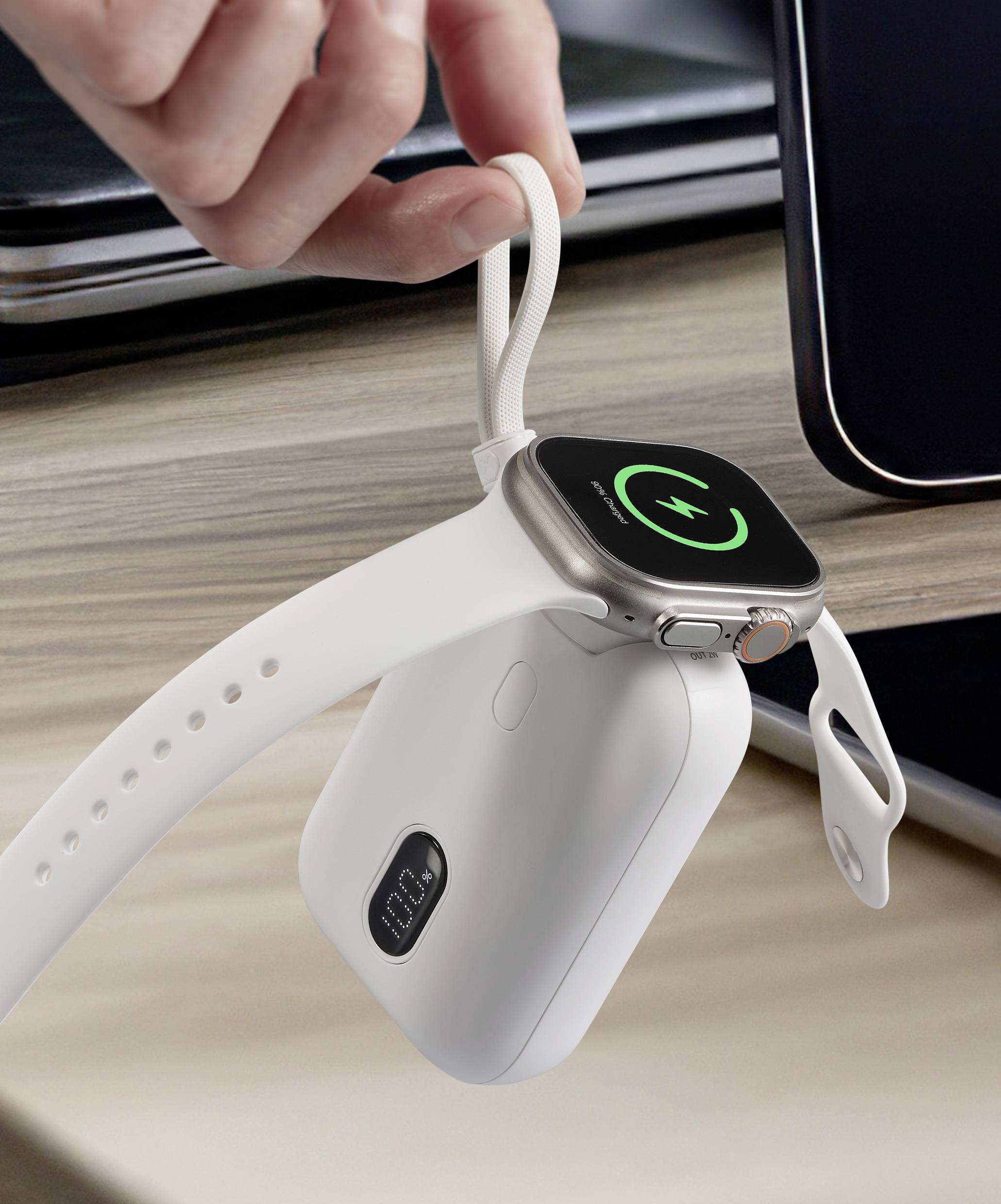 Eine Hand hält ein Ladegerät, an dem eine Smartwatch drahtlos aufgeladen wird. Der Bildschirm der Uhr zeigt ein Ladesymbol an.