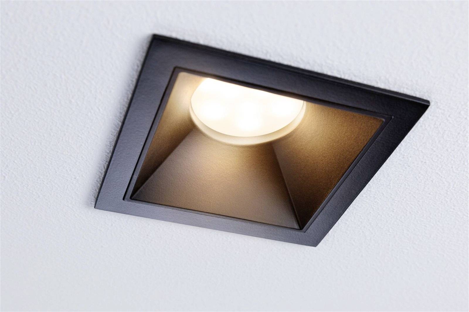 Schwarze quadratische Einbauleuchte mit LED, installiert in einer weißen Decke, strahlt warmes Licht ab.