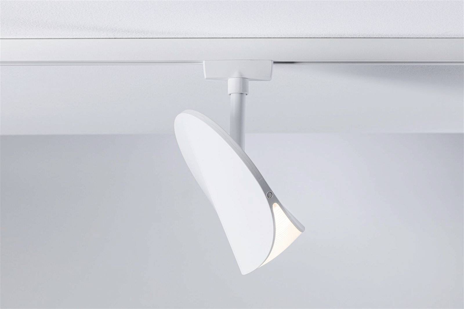 Weißer, moderner Deckenstrahler zeigt nach unten, montiert an einer Schiene an einer weißen Decke in einem minimalistischen Raum.