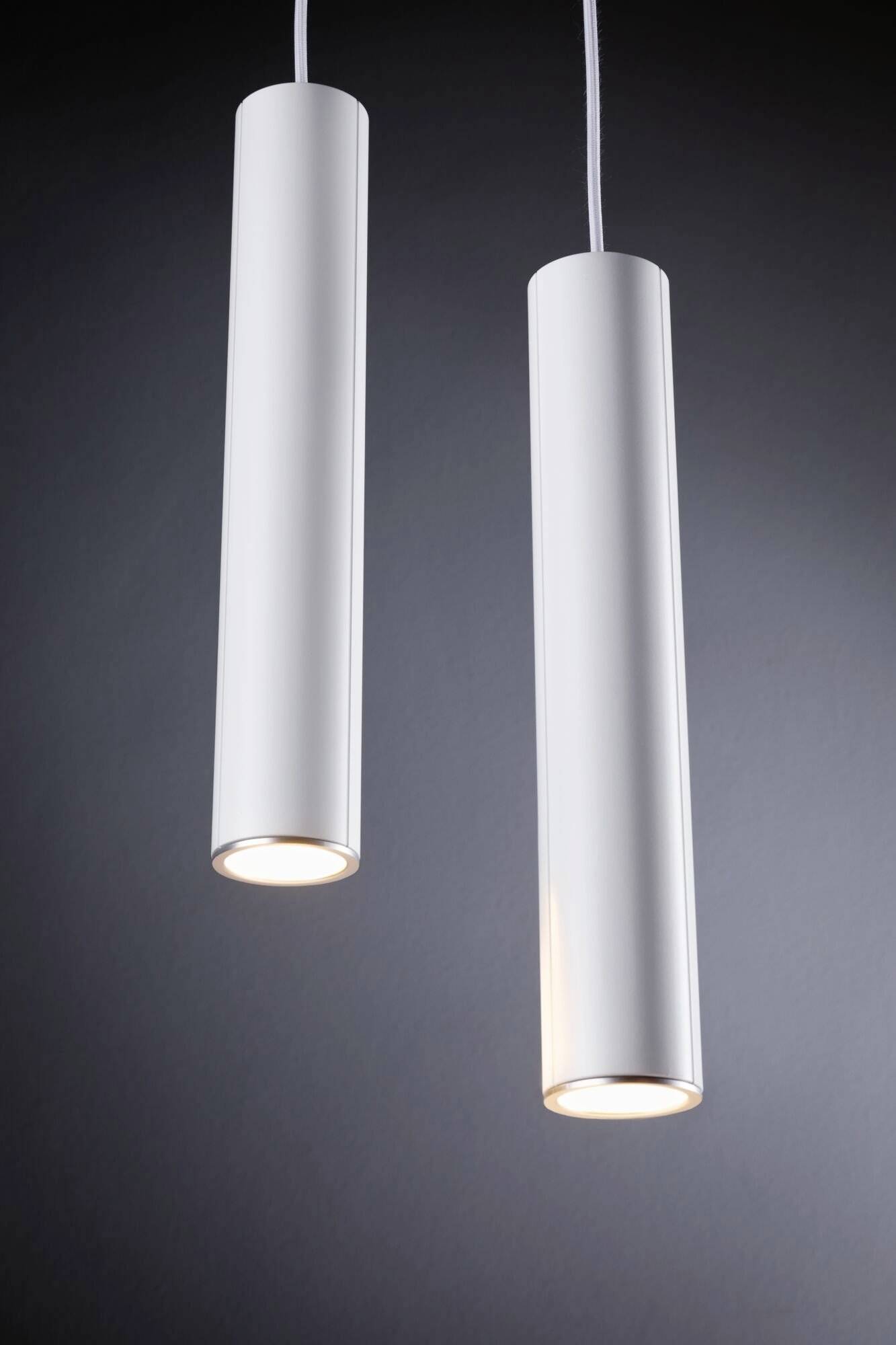 Zwei hängende, zylindrische weiße Lampen leuchten in einem dunklen Raum.