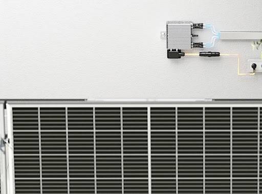 Ein Solarmodul mit einem angeschlossenen Wechselrichter an der Wand, der die erzeugte Energie umwandelt und ins Stromnetz speist.