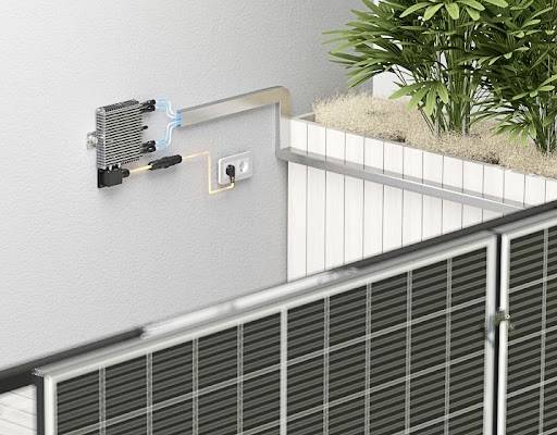 Solarmodul an einer Wand mit Steckdose, verbunden mit einem Kühlsystem. Daneben befindet sich ein Pflanzgefäß mit grünen Pflanzen.