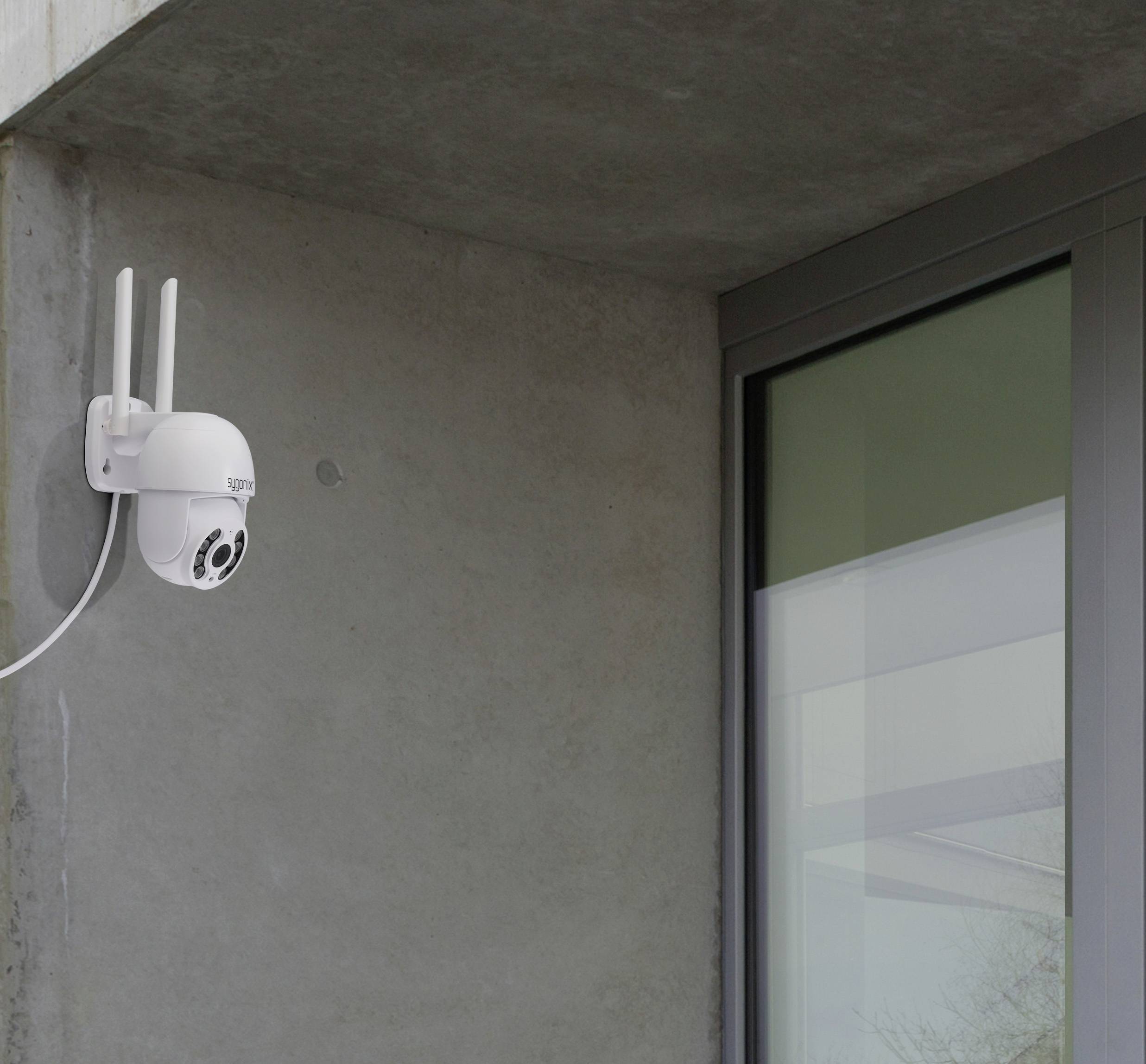 Eine Überwachungskamera ist an einer Gebäudeecke montiert, mit zwei Antennen und einem Kabel, das zur Stromversorgung oder Datenübertragung dient.