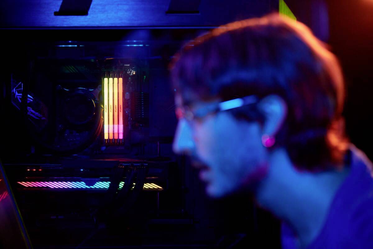 Unscharfe Nahaufnahme einer Person, die auf einen Computerbildschirm schaut. Im Hintergrund leuchten RGB-Lichter im Computergehäuse.