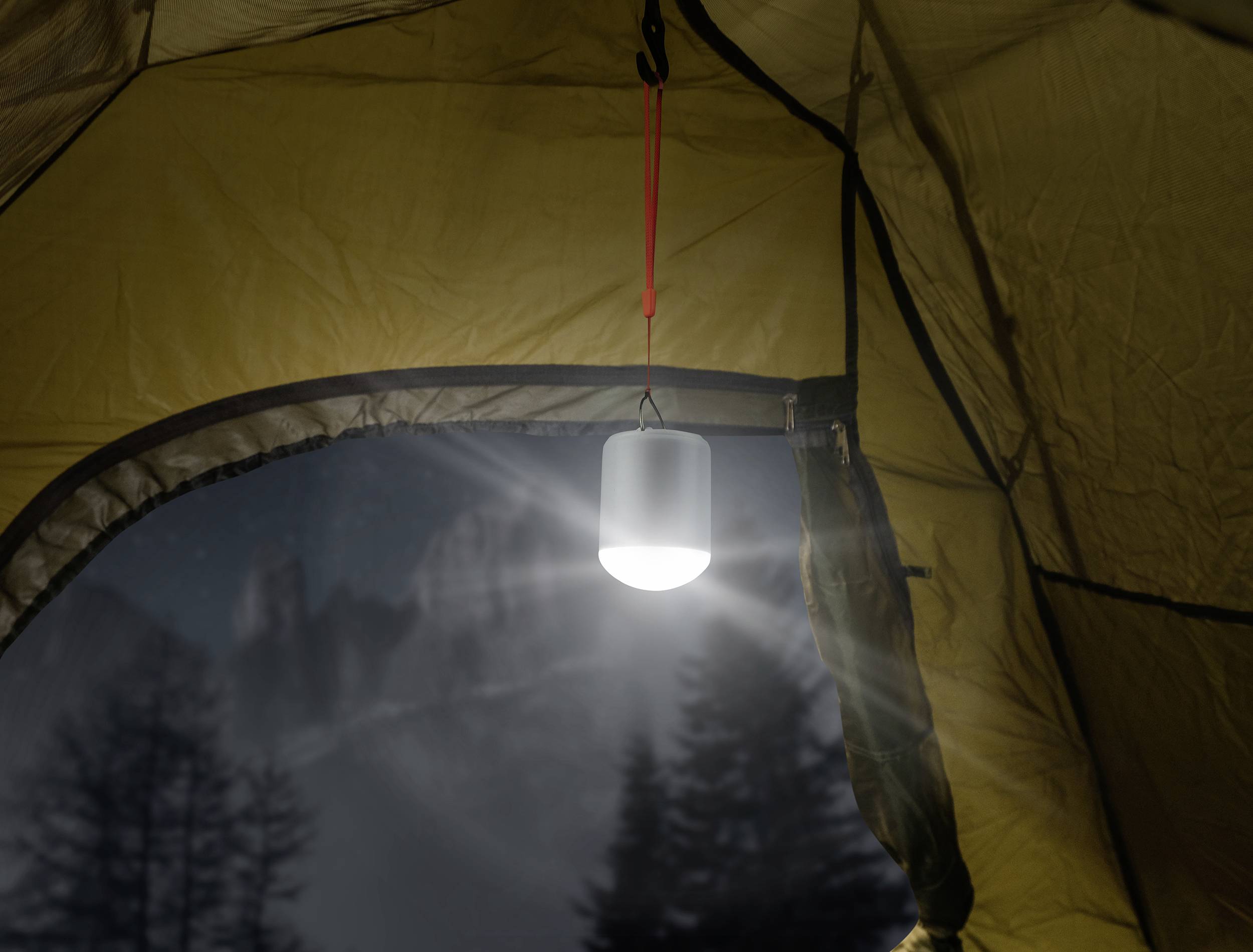 Eine beleuchtete Laterne hängt im Inneren eines Zeltes. Draußen sind unscharfe Bäume und Berge bei Nacht zu sehen.