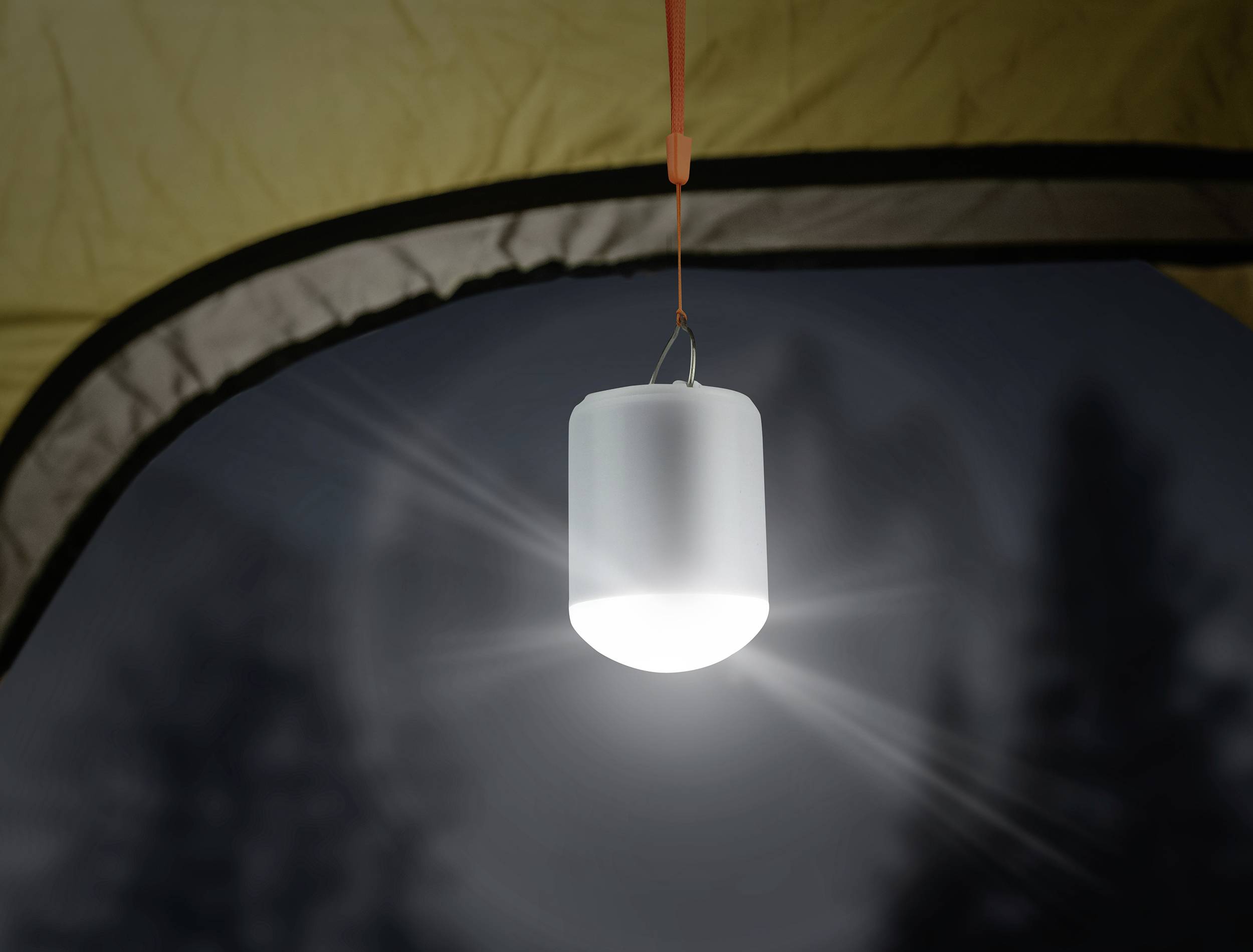 Eine leuchtende LED-Lampe hängt im Inneren eines Zeltes und erhellt die Umgebung in einer nächtlichen Waldszene.