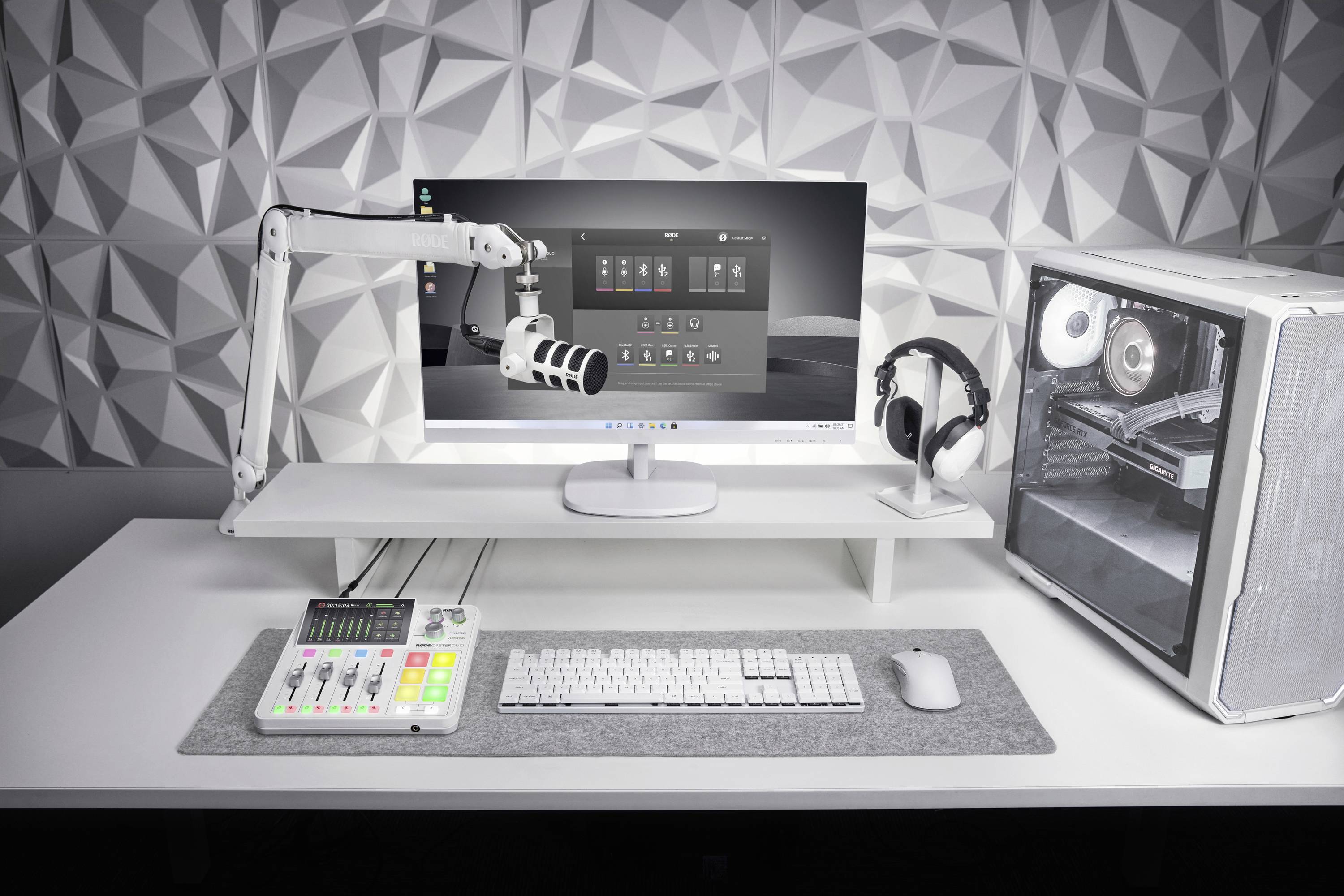 Moderner Arbeitsplatz mit Mikrofon, Computerbildschirm, weißem PC-Gehäuse, Tastatur und Kopfhörern. Aufnahme- und Streaming-Setup.