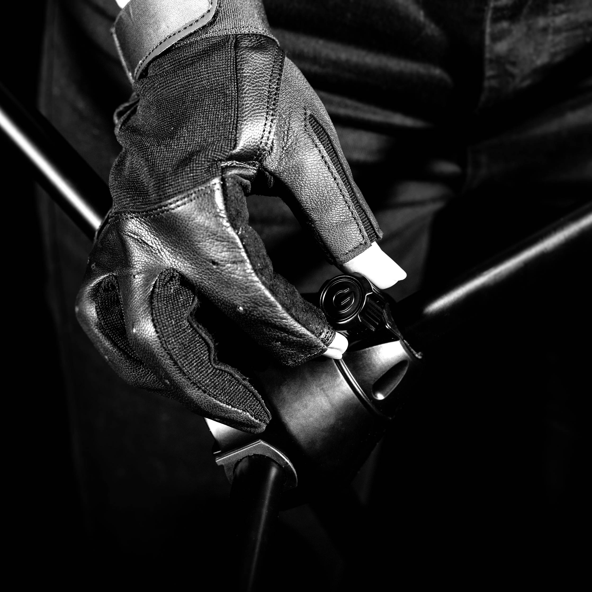 Hand in einem Motorradhandschuh hält den Lenker eines Motorrads.