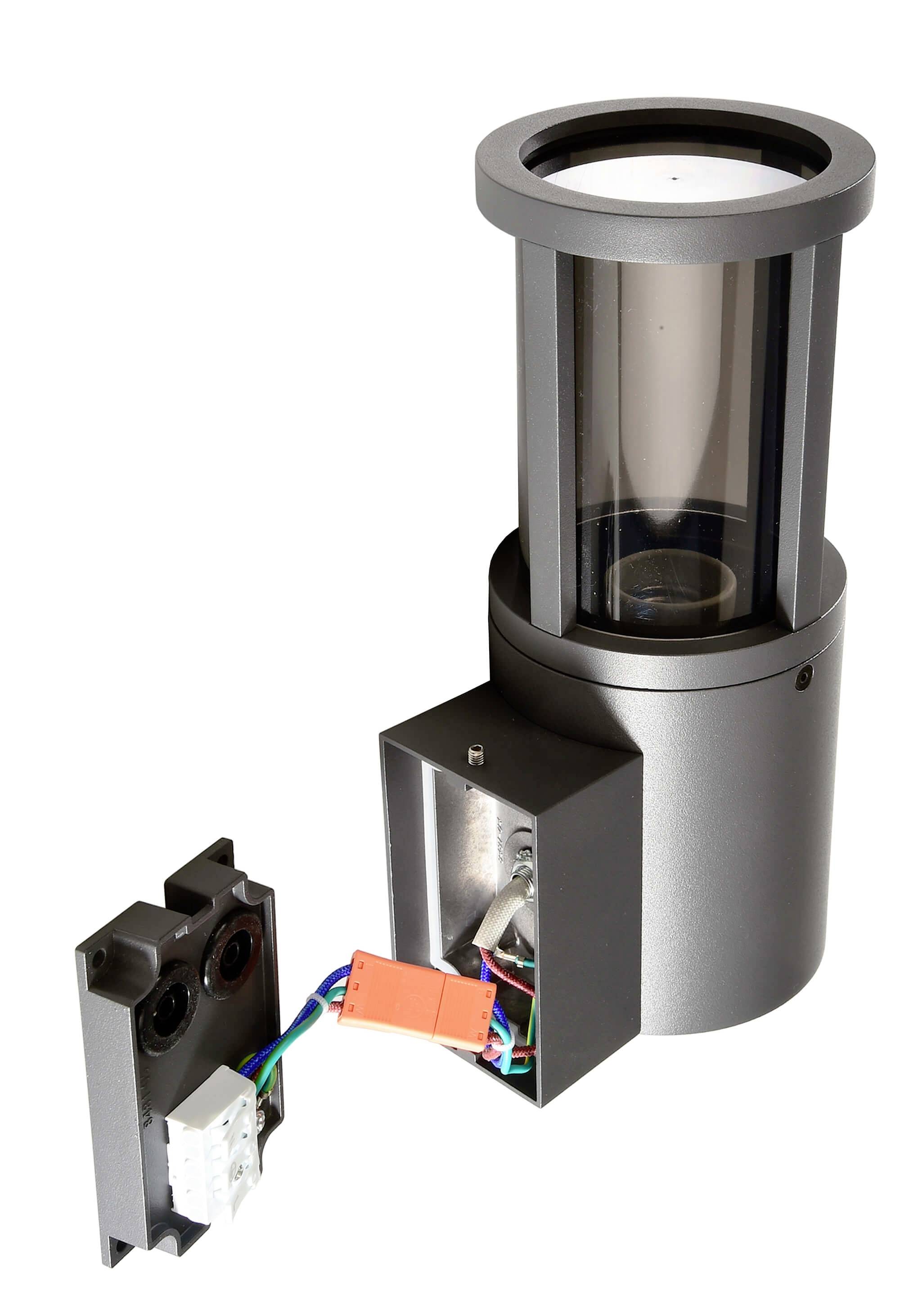 Eine moderne, zylinderförmige Bodenleuchte aus Metall mit einem abnehmbaren Anschlusskasten, sichtbar mit Kabeln und Steckverbindungen.