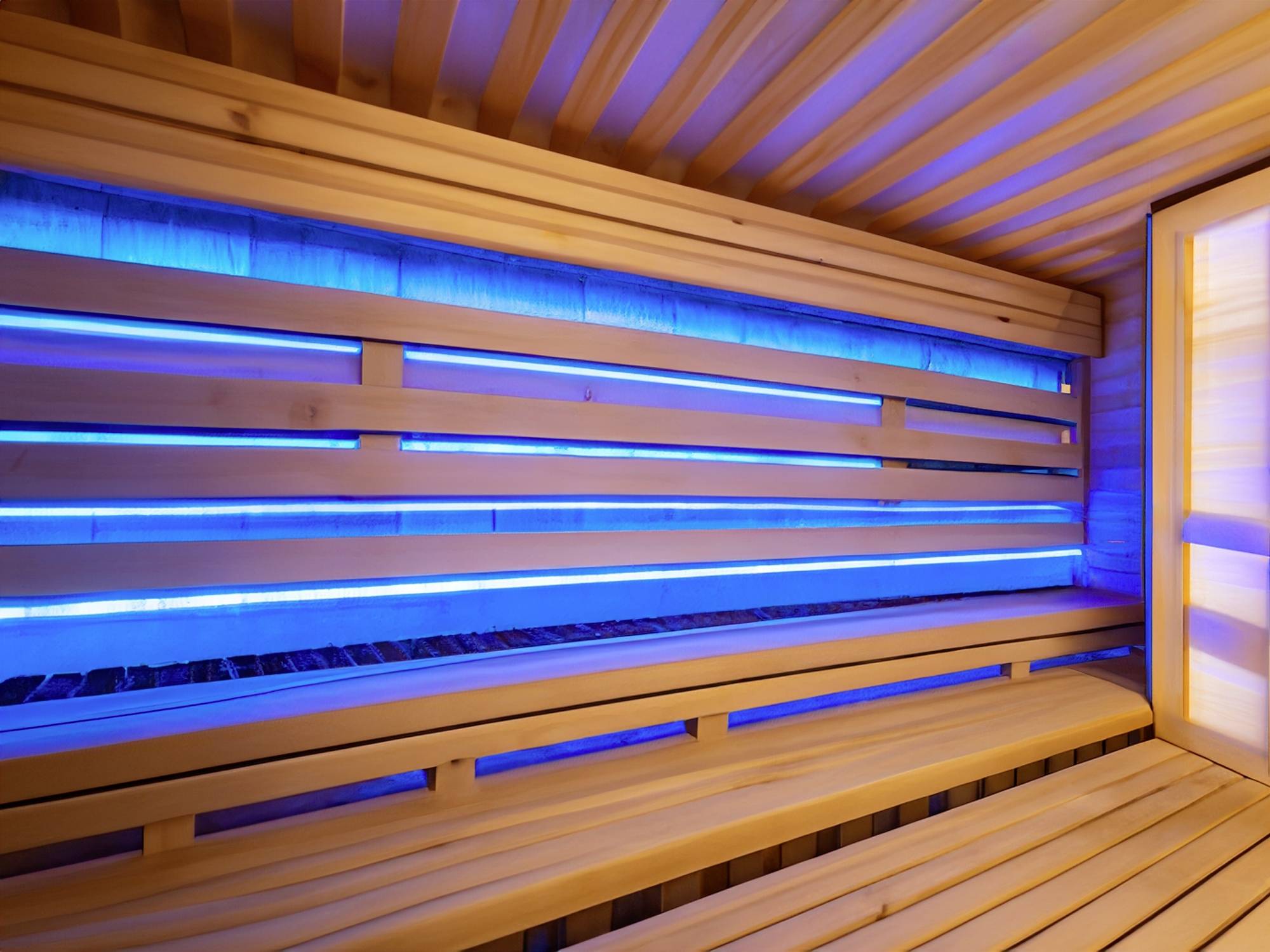 Holzsauna von innen mit blauem LED-Licht. Die Holzbänke sind leer und das Licht verleiht dem Raum eine beruhigende Atmosphäre.