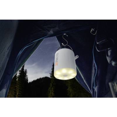 Zelt mit integrierter LED-Lampe, die im Dunkeln leuchtet. Der Himmel ist sternenklar mit Umrissen von Bäumen im Hintergrund.
