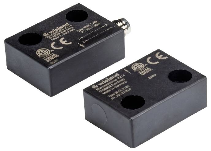 Zwei schwarze, rechteckige elektronische Sensoren, jeweils mit CC- und CE-Kennzeichnungen, nahe beieinander liegend.