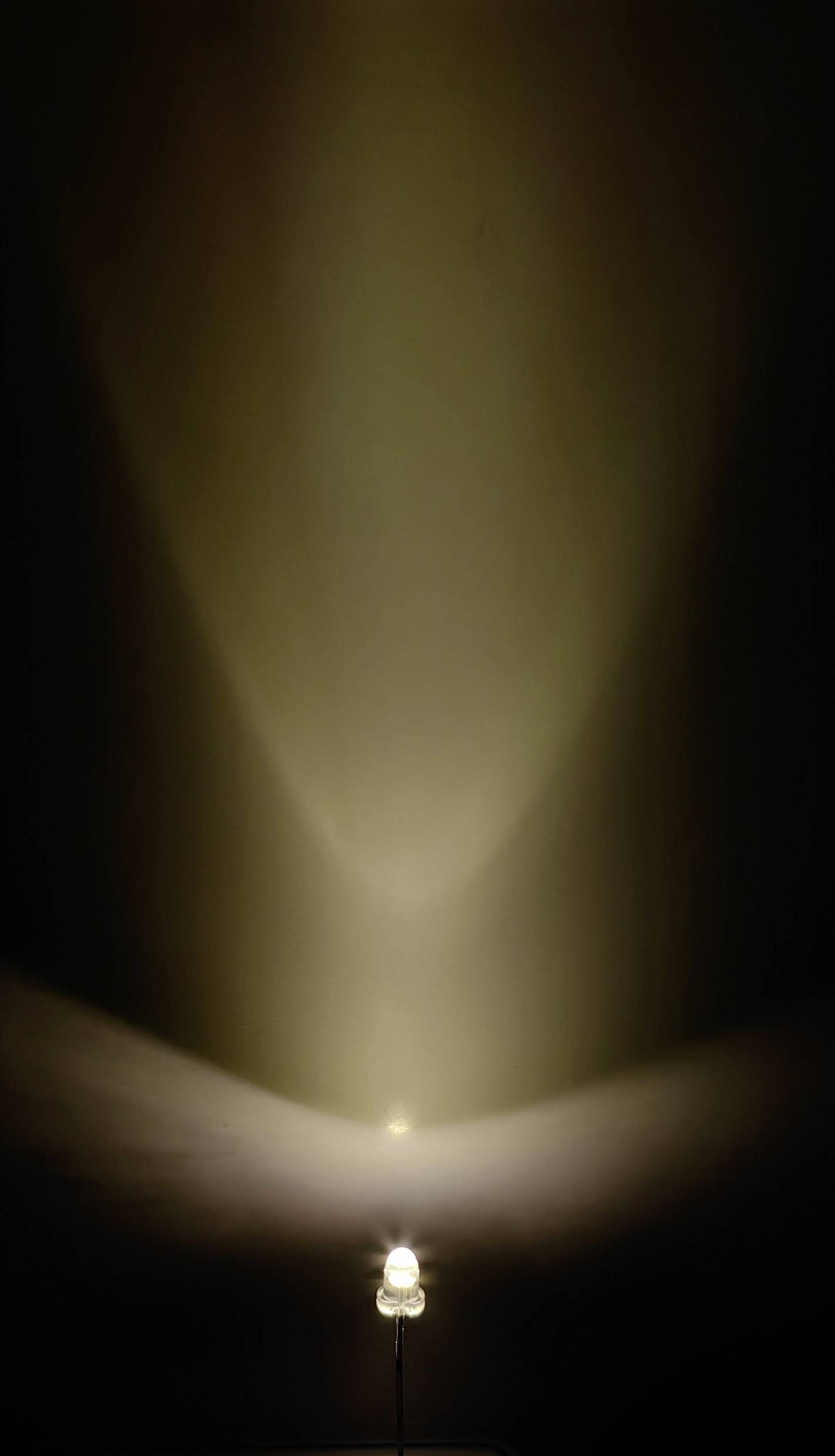 Eine einzelne Glühbirne strahlt Licht an eine Wand, erzeugt einen sanften Lichtkegel in dunklem Hintergrund.