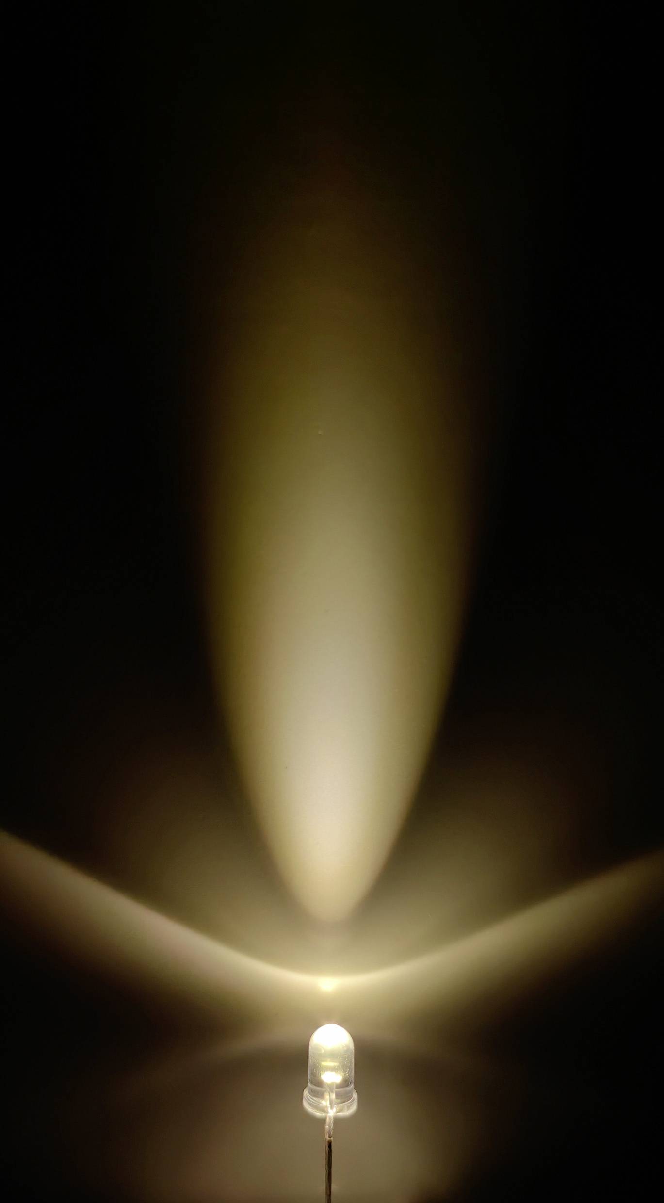 Eine eingeschaltete LED-Lampe strahlt Licht in einem dreieckigen Muster nach oben und unten aus, auf dunklem Hintergrund.
