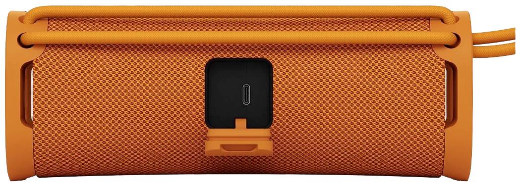Ein orangefarbener, tragbarer Lautsprecher mit einem Gittermuster; Rückansicht zeigt einen USB-Anschluss in der Mitte.