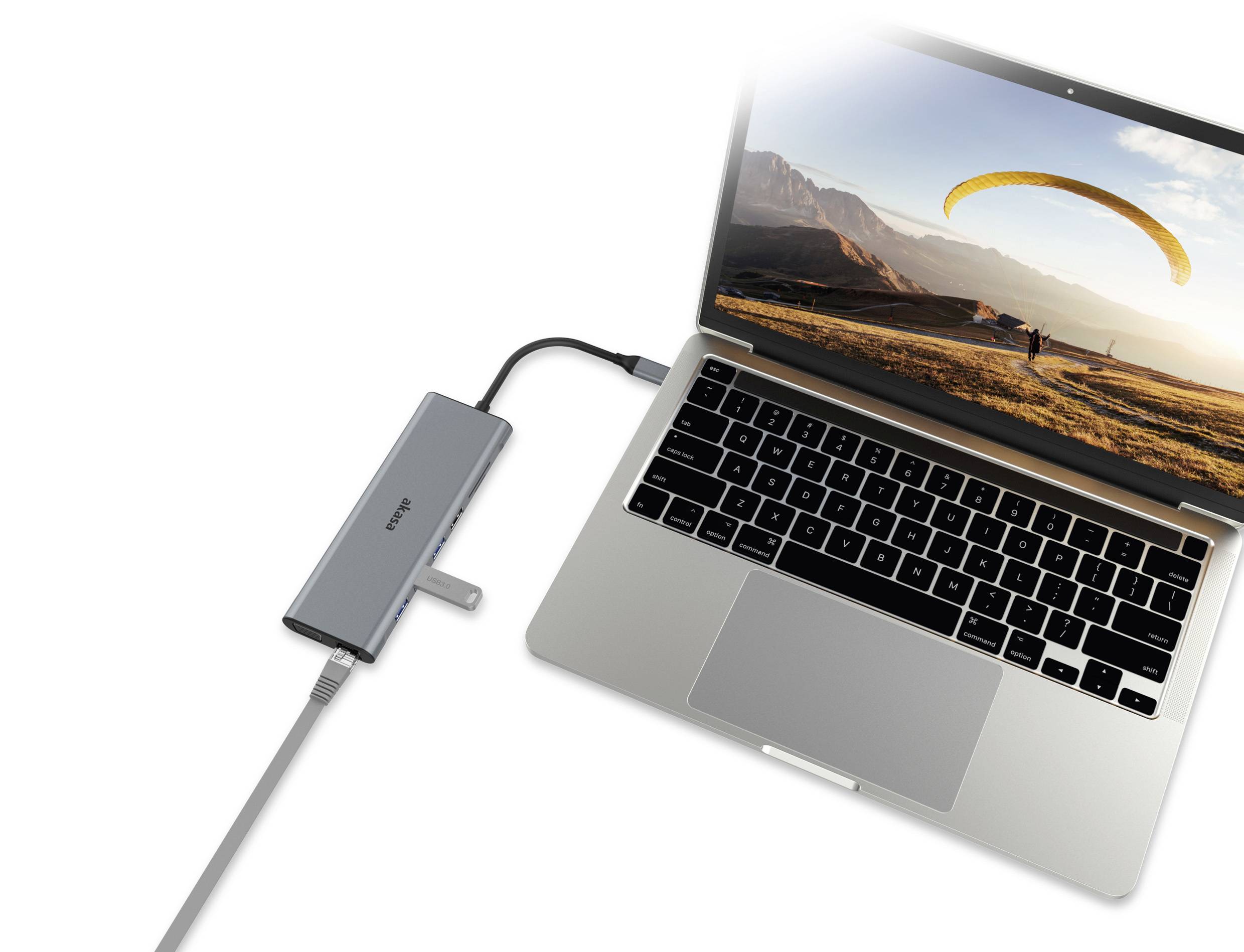 Ein Laptop zeigt ein Foto eines Paraglidings über einer Landschaft. Ein USB-C-Hub ist an den Laptop angeschlossen.