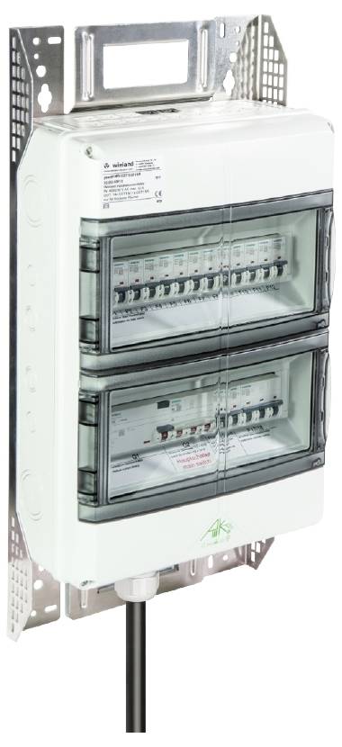 Ein elektrischer Verteilerkasten mit zwei Reihen von Schaltern, montiert an einer Wandhalterung, zeigt Schaltungen und Prüfzeichen.