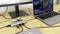 Ein Laptop ist über mehrere Kabel und Adapter mit einem Monitor verbunden. Auf dem Monitor sind Menüoptionen zu sehen.