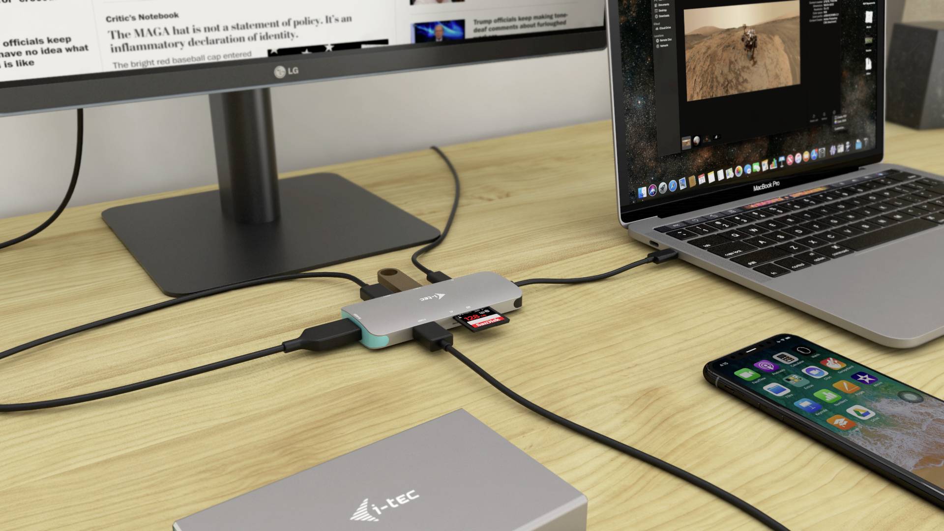 Ein Schreibtisch mit Laptop, zwei Bildschirmen und mehreren angeschlossenen Peripheriegeräten über USB-Hubs. Ein Smartphone liegt daneben.