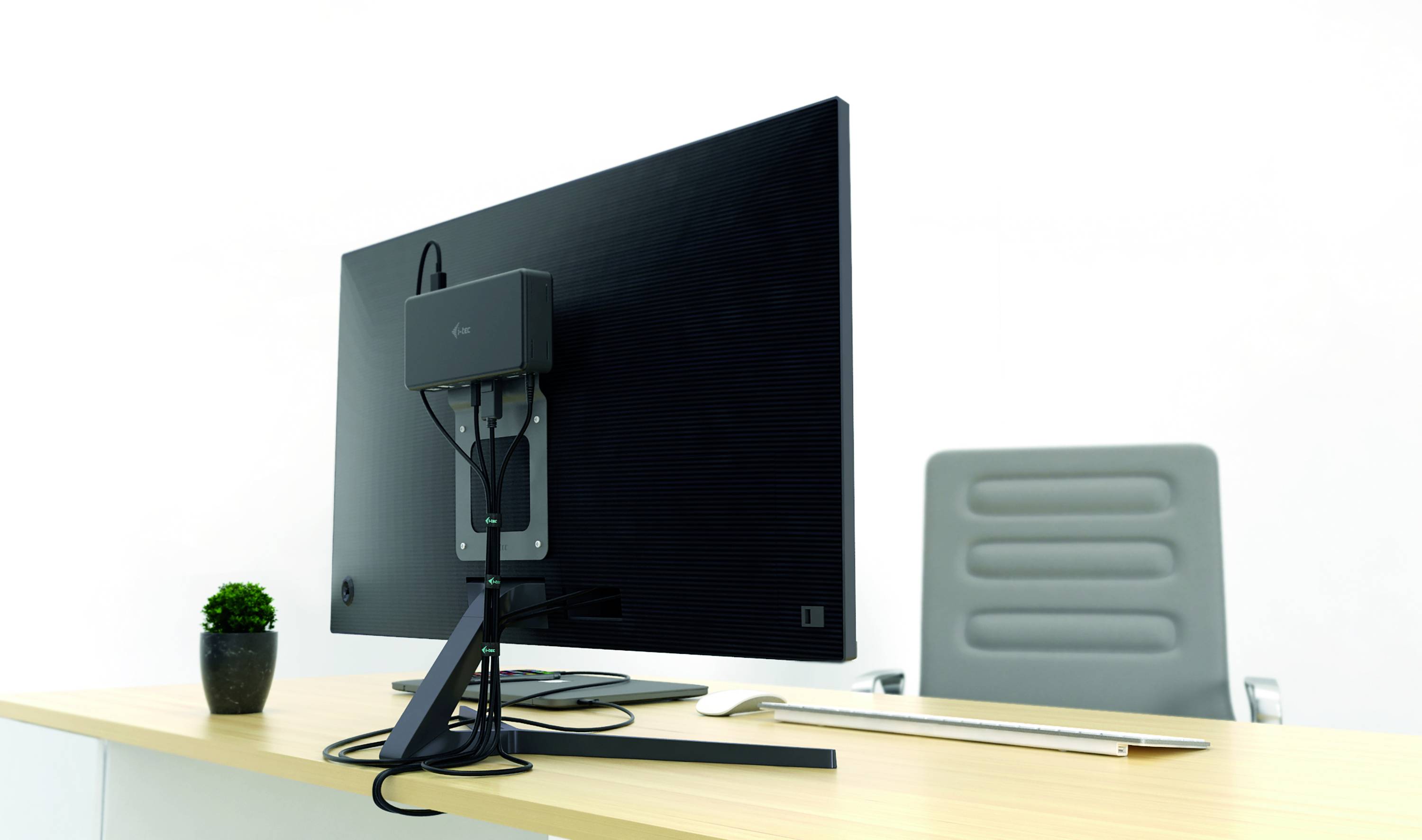 Ein leeres Büro mit einem Schreibtisch, auf dem ein Monitor, eine Tastatur und eine kleine Pflanze stehen. Ein Bürostuhl ist im Hintergrund.