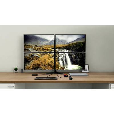Vier verbundene Monitore zeigen ein Landschaftsbild mit einem Wasserfall und Bergen. Eine Tastatur und Maus liegen davor.