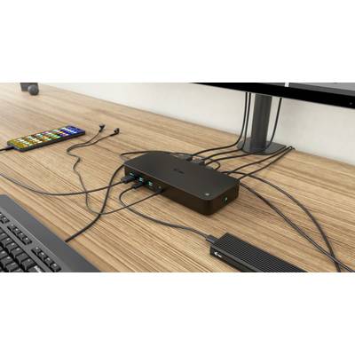 'USB-Dockingstation mit mehreren angeschlossenen Kabeln auf einem Schreibtisch. Verbindet Laptop, Smartphone und Peripheriegeräte.'