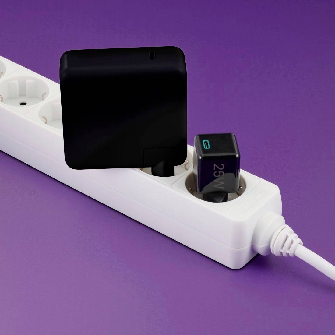 Mehrfachsteckdose mit zwei eingesteckten schwarzen Ladegeräten auf violettem Hintergrund.