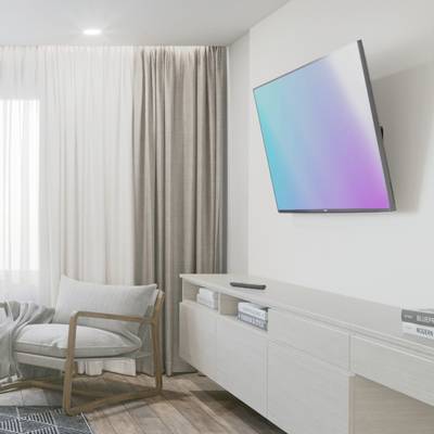 Helles Wohnzimmer mit Sessel links, bodenlangen Vorhängen und einem Flachbildfernseher rechts an der Wand über einem Sideboard.