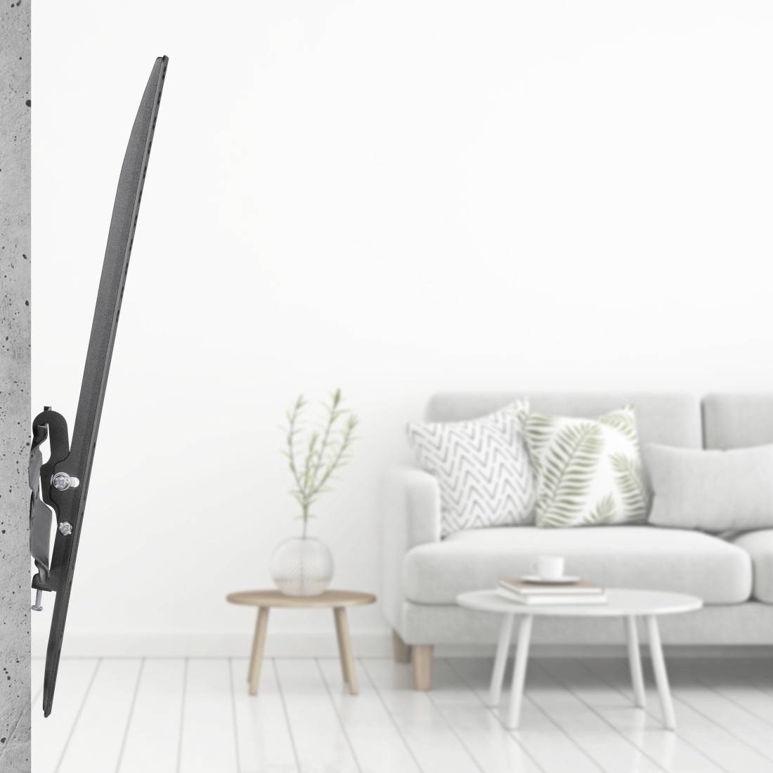 Ein schwarz-weißes Skateboard lehnt an einer grauen Wand in einem minimalistisch eingerichteten Wohnzimmer mit Sofa, Tisch und Pflanze.