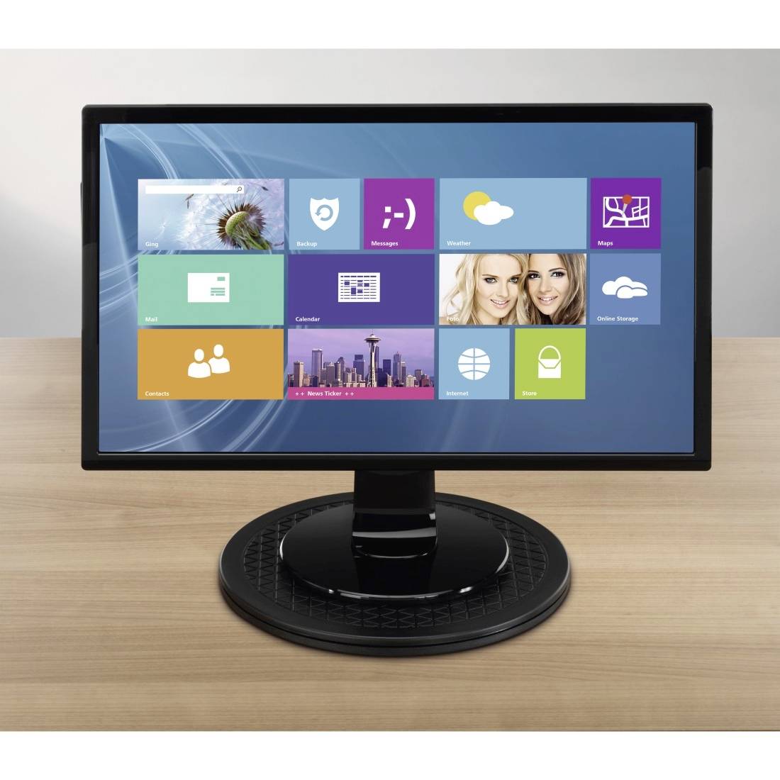 Ein Computerbildschirm zeigt eine Kacheloberfläche mit Symbolen für Apps und Widgets auf einem Holztisch.
