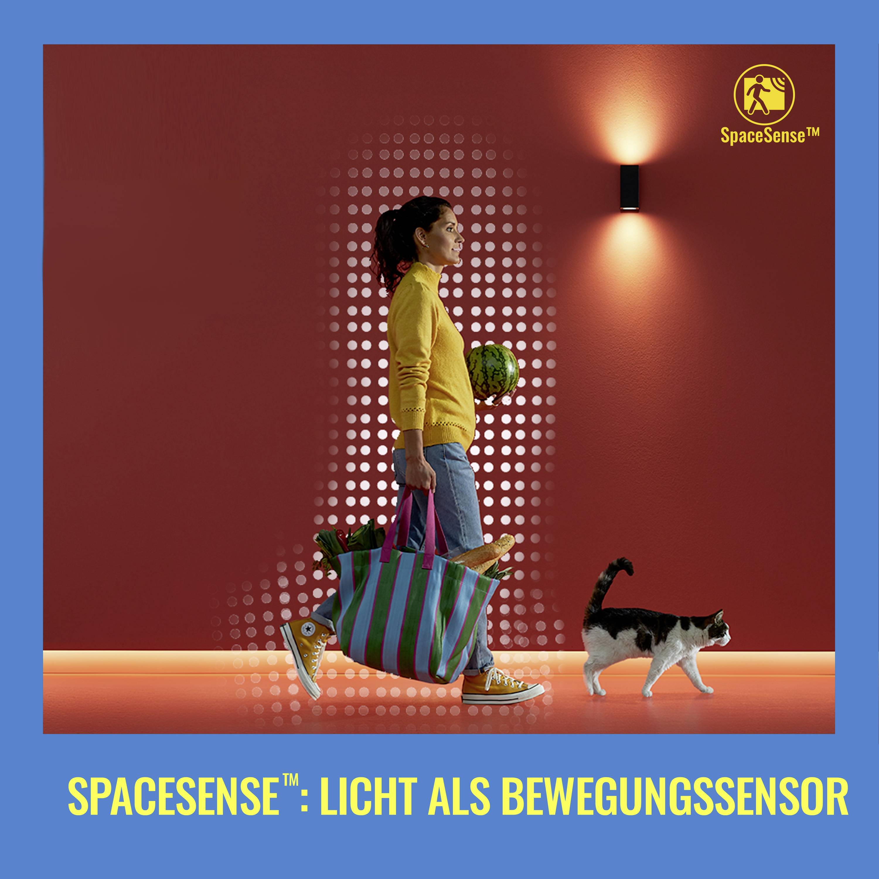 Frau trägt Einkaufstaschen, geht an beleuchteter Wand entlang. Katze folgt. Schriftzug unten: 'SpaceSense™: Licht als Bewegungssensor'.