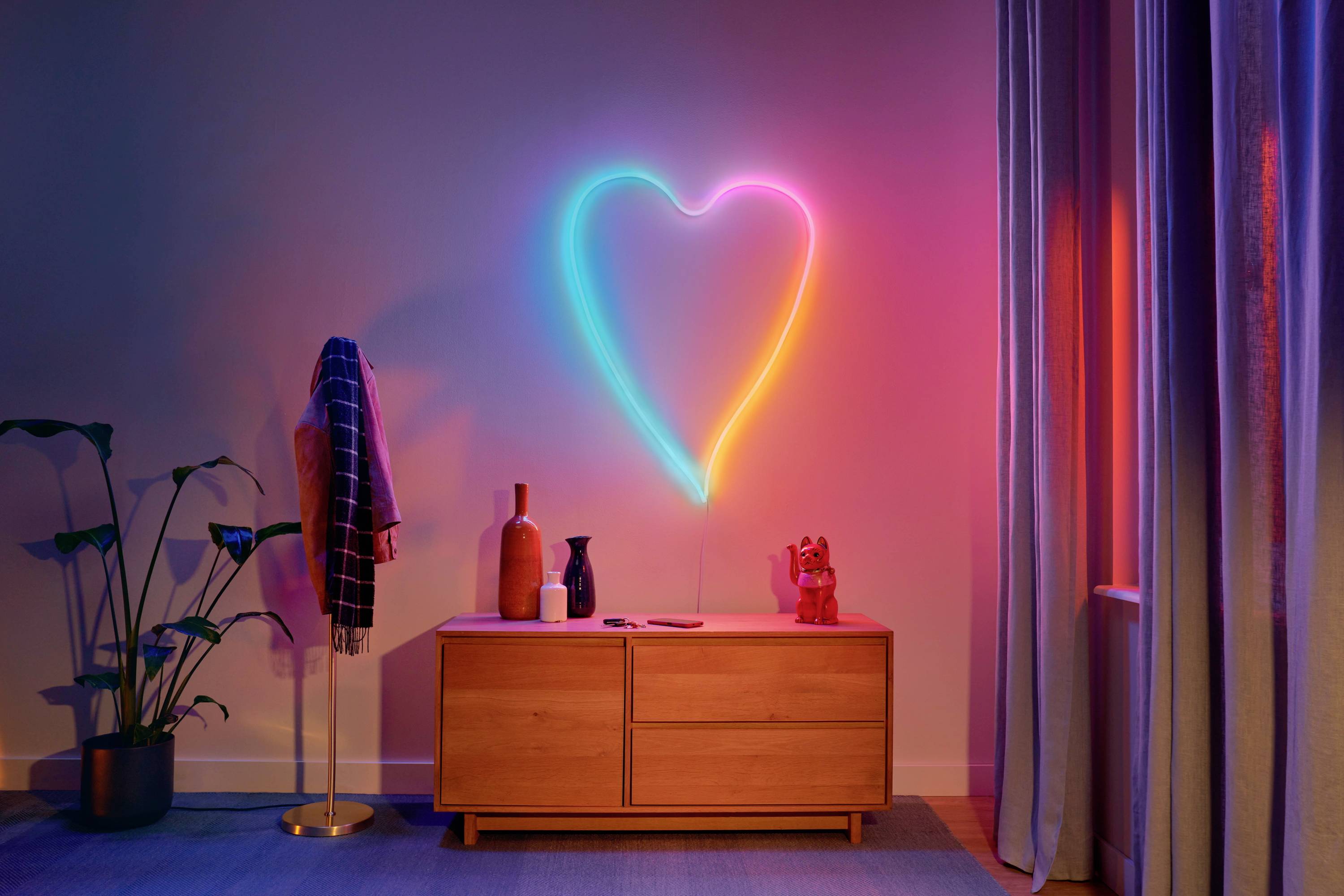 Ein Wohnzimmer mit einer Kommode, auf der verschiedene Dekorationsgegenstände stehen. An der Wand leuchtet ein neonfarbenes Herz.