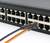 Ein schwarzer Netzwerk-Switch mit einem orangenen Ethernet-Kabel, das in einen der Ports eingesteckt ist.