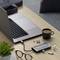 Ein Laptop auf einem Tisch, verbunden mit einem USB-Hub, daneben eine Tasse Kaffee, eine Kamera-Speicherkarte, eine Brille und eine Pflanze.
