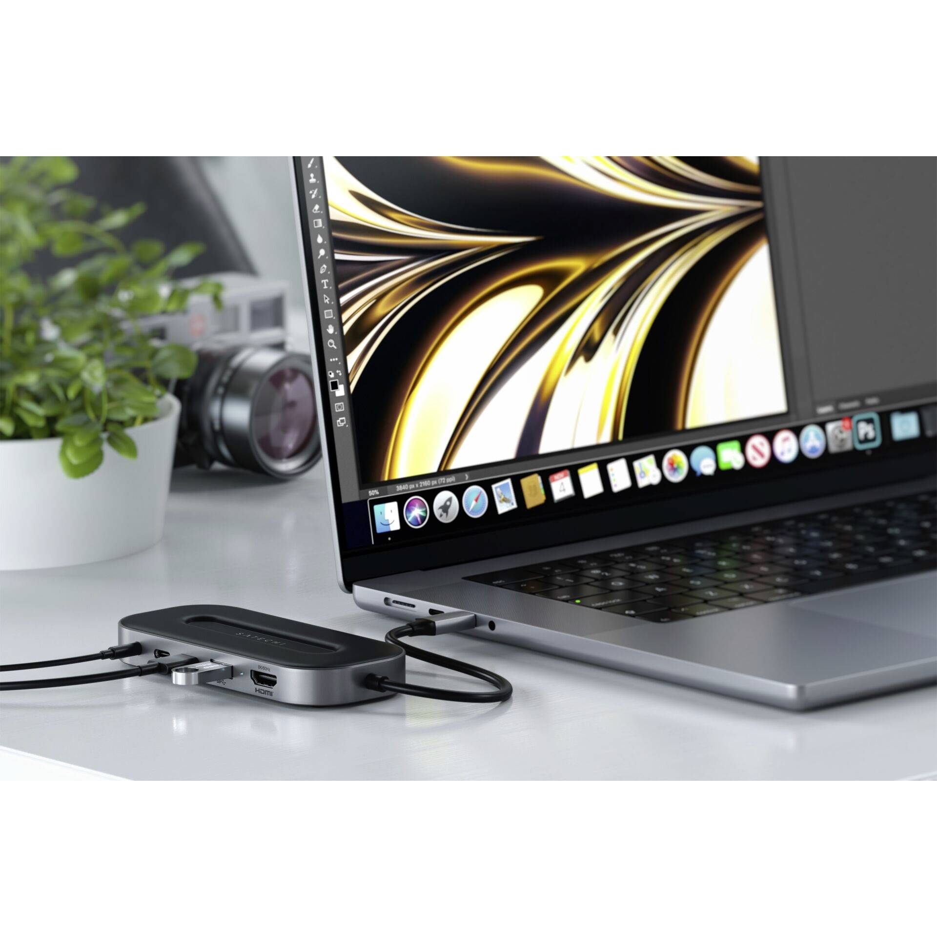 Ein Laptop mit einem geöffneten Grafikprogramm zeigt ein abstraktes Kunstwerk. Daneben steht eine Kamera und ein USB-Hub mit Kabel.