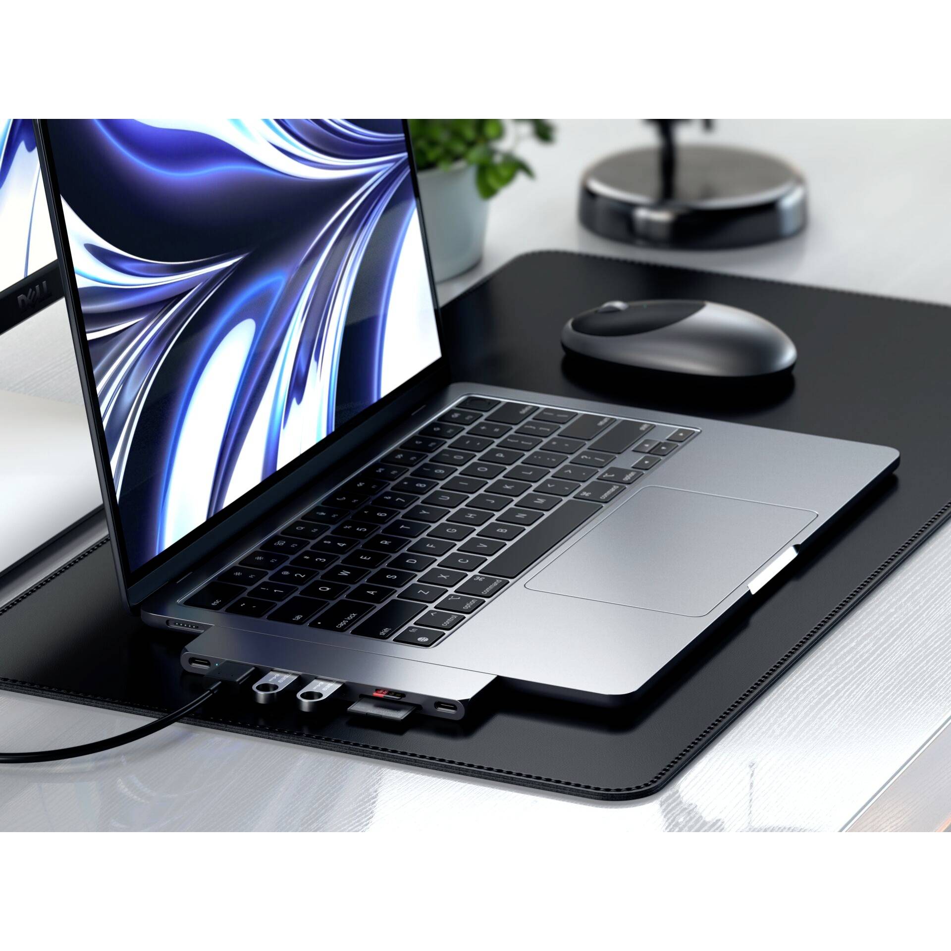 Schlanker Laptop auf Schreibtisch neben Maus. Display zeigt abstrakte blaue Muster. Laptop hat mehrere angeschlossene Kabel.