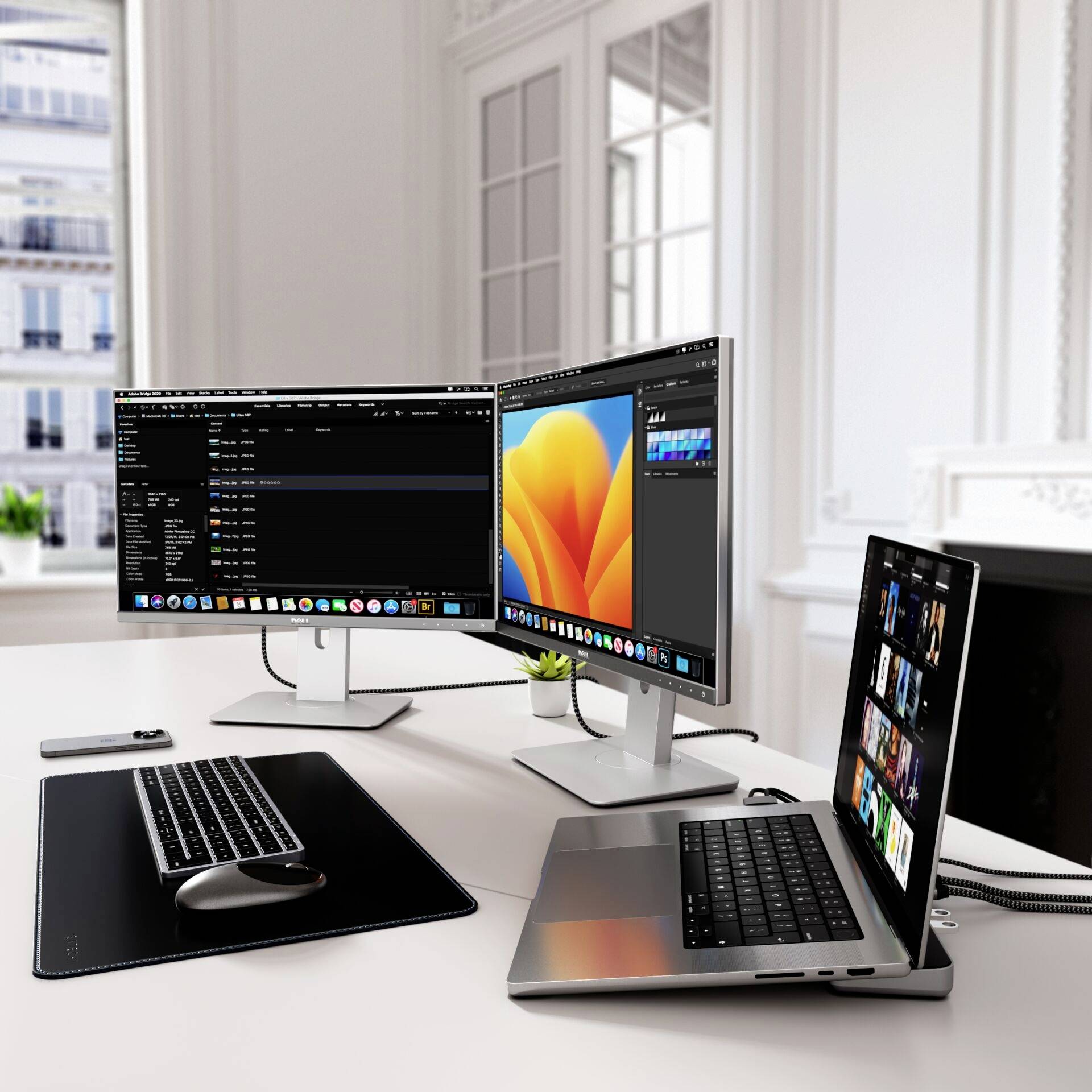 Ein moderner Schreibtisch mit zwei Monitoren und einem Laptop, auf denen unterschiedliche Arbeitsprogramme geöffnet sind; Bürofenster im Hintergrund.