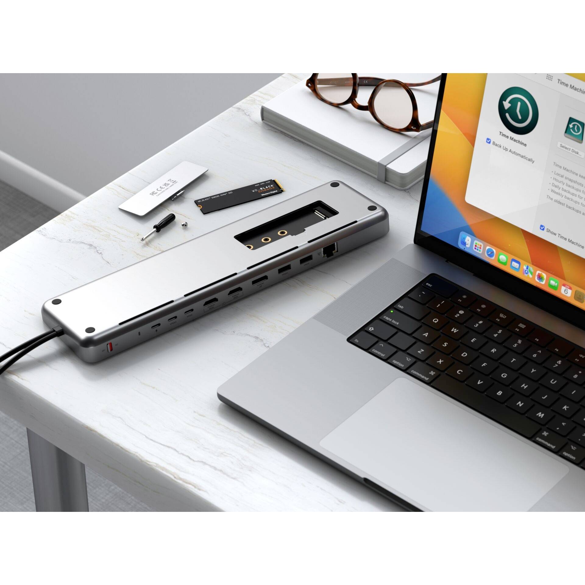 Ein Laptop auf einem Tisch zeigt einen Bildschirm mit einem Software-Update. Neben ihm liegt ein offenes Dock mit mehreren Anschlüssen.