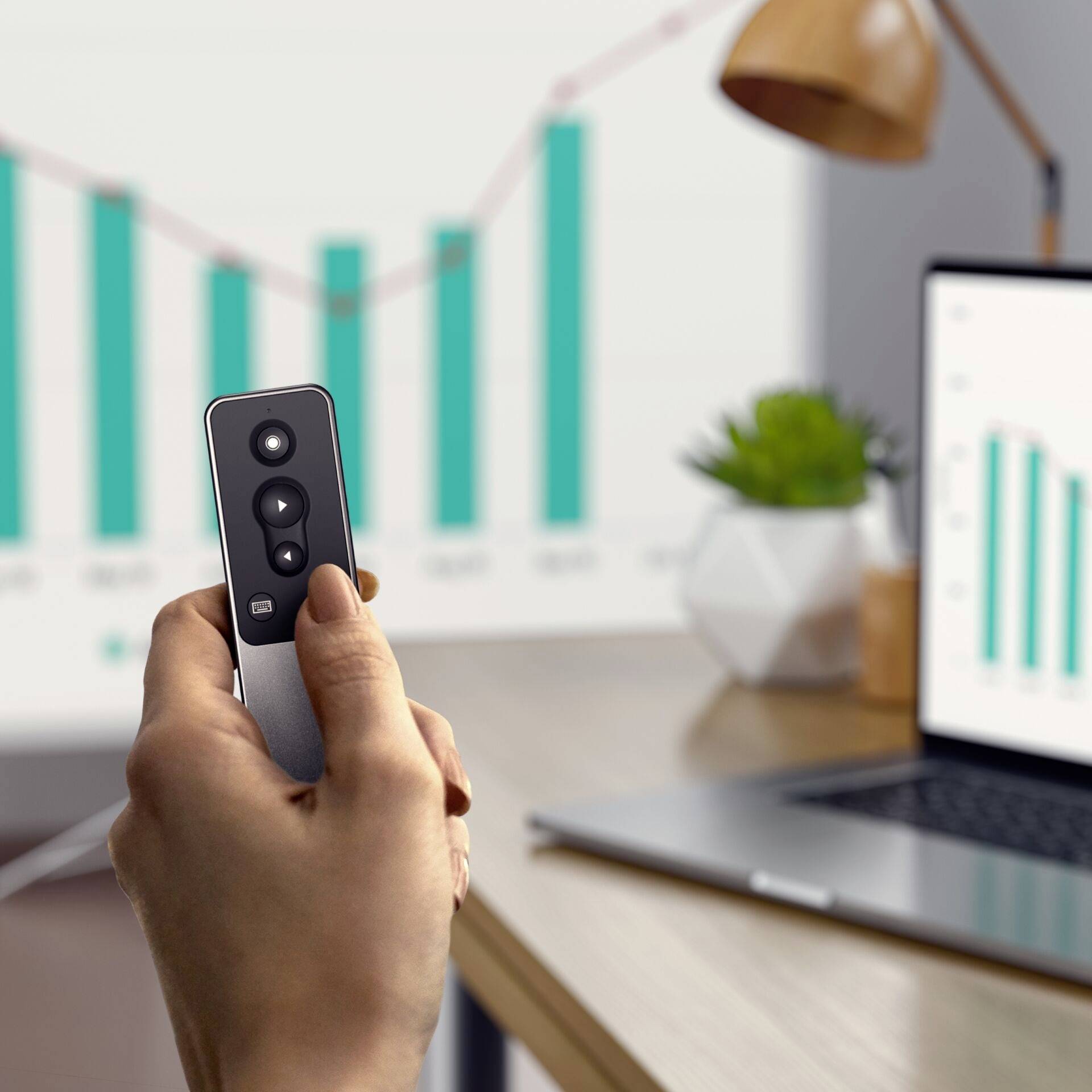 Eine Hand hält eine Fernbedienung vor einem Laptop-Bildschirm, der ein Balkendiagramm mit steigender Tendenz zeigt.