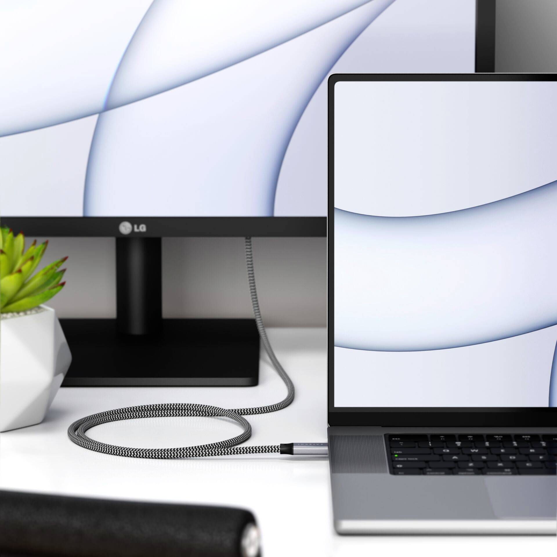 Ein Laptop und ein Monitor auf einem weißen Schreibtisch; beide zeigen ein ähnliches weiß-blaues Muster auf ihren Bildschirmen.